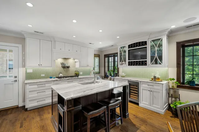 a kitchen with granite countertop a stove a sink a dining table and chairs