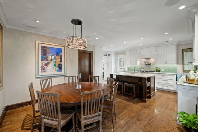 a dining room with wooden floor a chandelier a wooden table and chairs