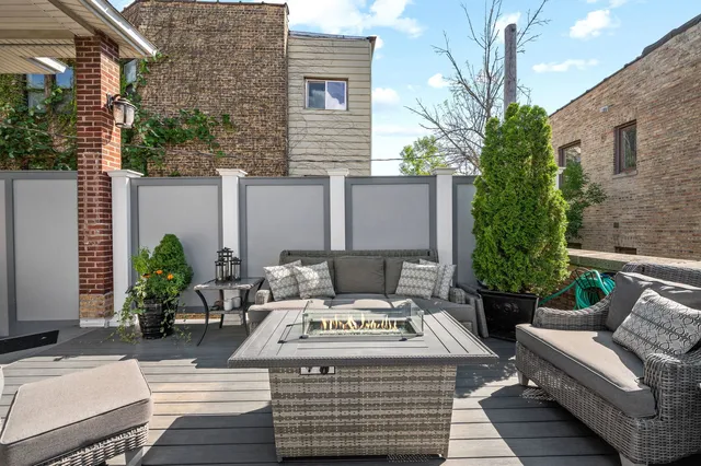 a view of a patio with couches table and chairs with wooden floor and fence