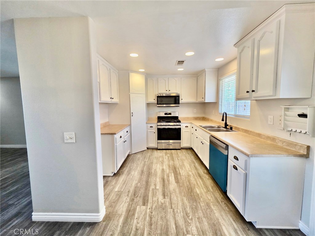 15354 Kiamichi Road Apple Valley, CA 92307 - Photo 7 of 22 a kitchen with granite countertop a sink a counter top space stainless steel appliances and cabinets