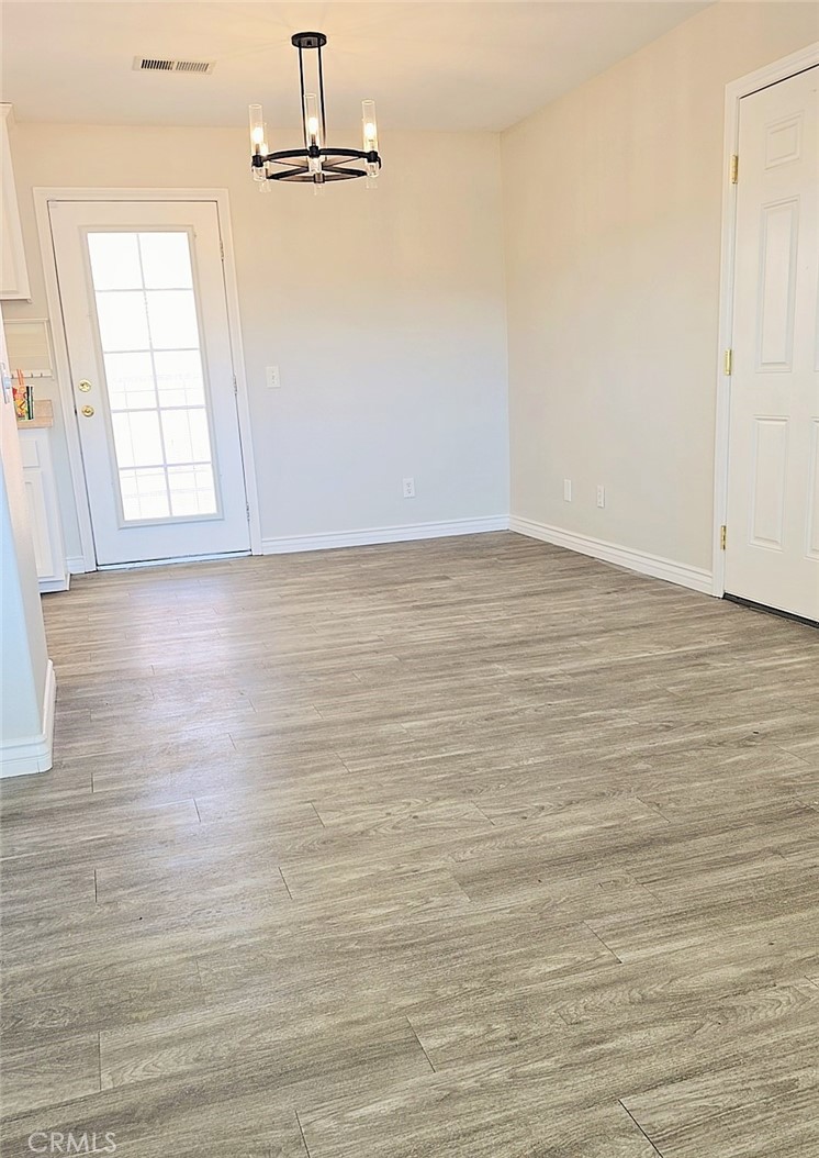 15354 Kiamichi Road Apple Valley, CA 92307 - Photo 9 of 22 an empty room with wooden floor fan and windows
