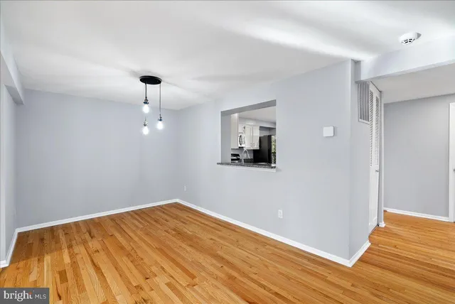 a view of an empty room with window and wooden floor
