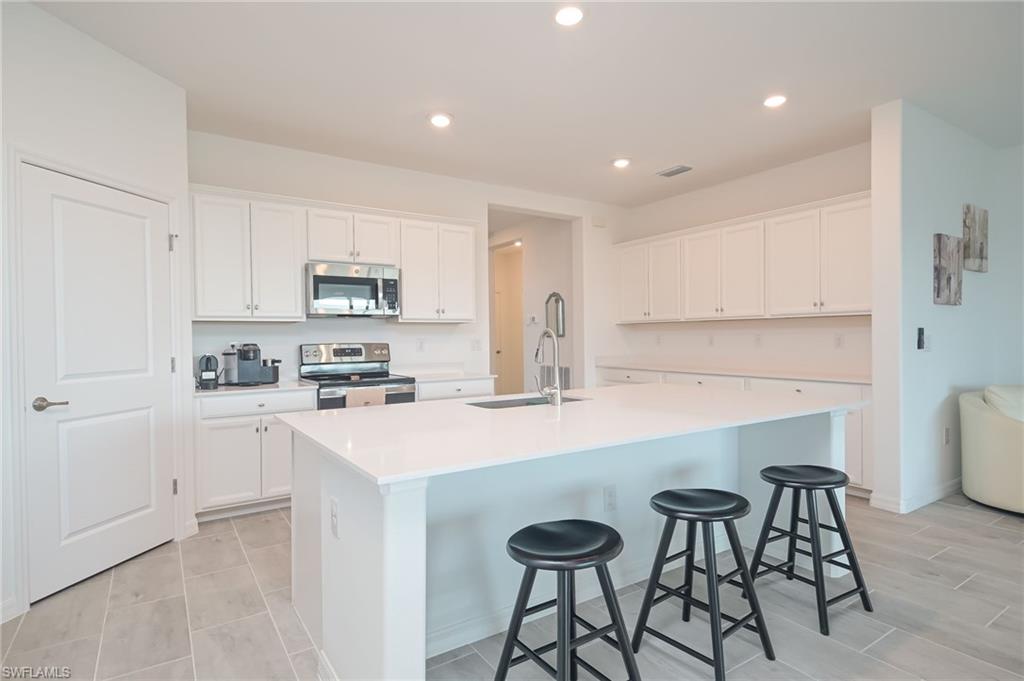 2532 Kona Way Naples, FL 34120 - Photo 7 of 30 a kitchen with stainless steel appliances a sink a stove a refrigerator cabinets and a dining table