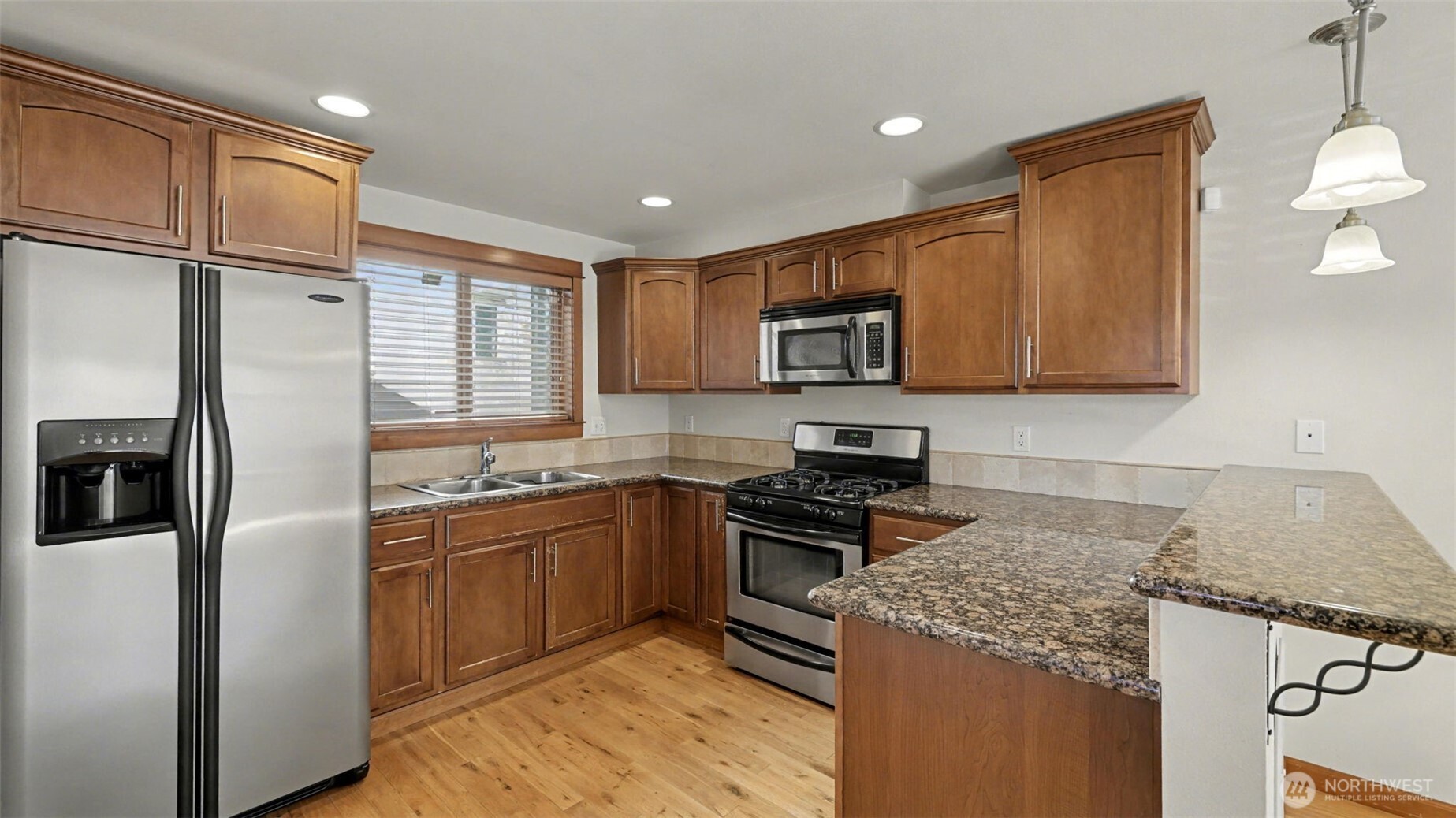 1120 North 92nd Street, Unit A Seattle, WA 98103 - Photo 5 of 22 a kitchen with kitchen island granite countertop a sink stove and refrigerator