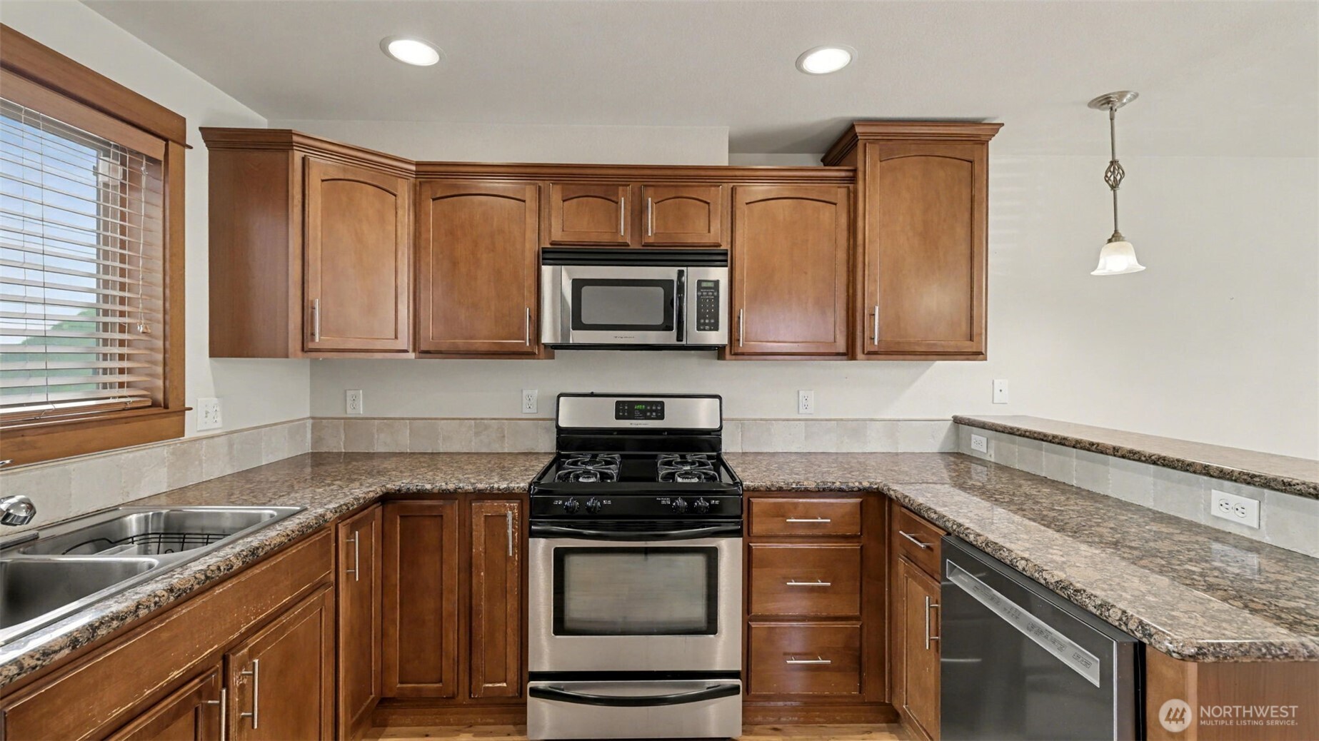 1120 North 92nd Street, Unit A Seattle, WA 98103 - Photo 6 of 22 a kitchen with granite countertop stainless steel appliances and wooden cabinets