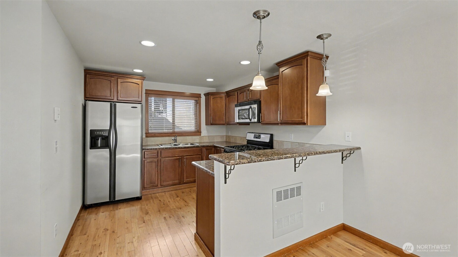 1120 North 92nd Street, Unit A Seattle, WA 98103 - Photo 7 of 22 a kitchen with stainless steel appliances granite countertop a refrigerator a sink a stove and a microwave