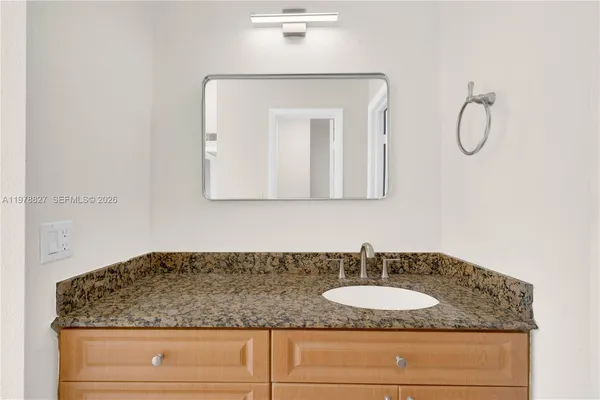 a bathroom with a granite countertop sink and a mirror
