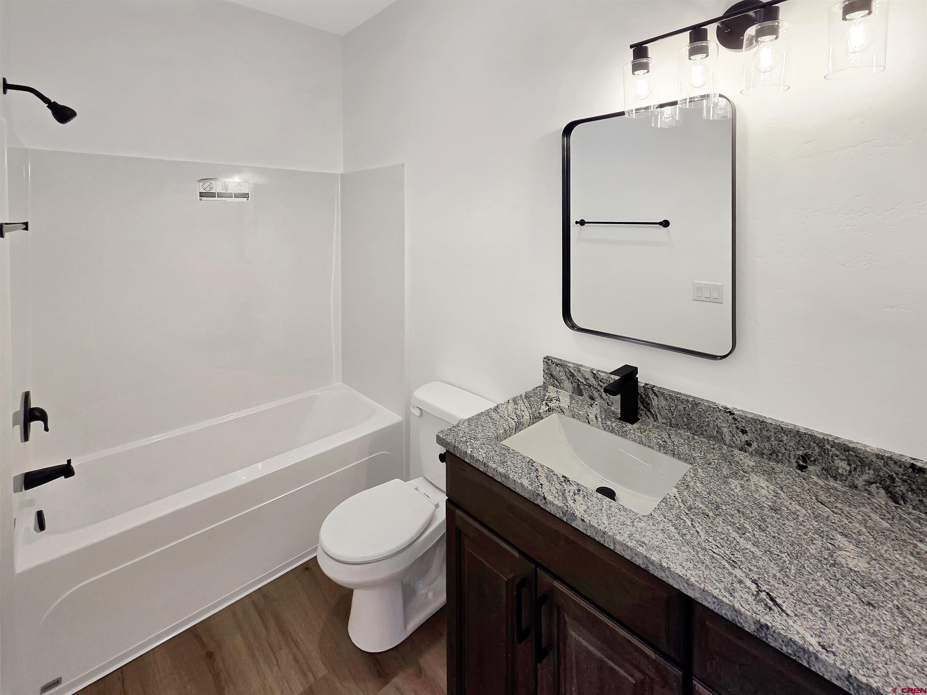 1456 Acoma Street Cortez, CO 81321 - Photo 17 of 26 a bathroom with a granite countertop sink toilet a large mirror and bathtub
