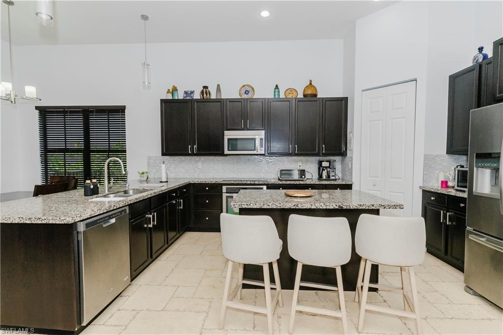 5169 Roma Street South Ave Maria, FL 34142 - Photo 13 of 49 a kitchen with stainless steel appliances granite countertop a sink and a refrigerator