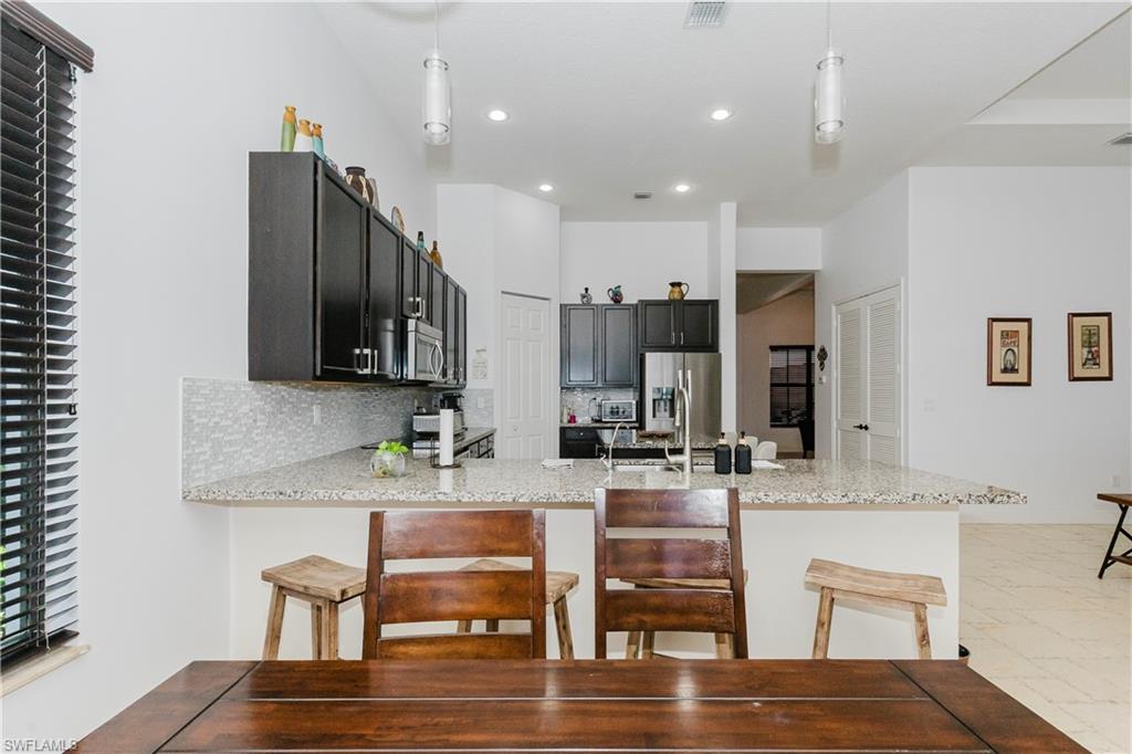 5169 Roma Street South Ave Maria, FL 34142 - Photo 17 of 49 a kitchen with kitchen island granite countertop a view of chairs and wooden floor