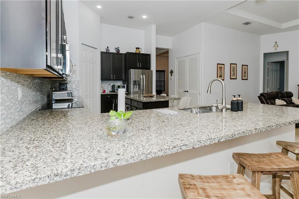 5169 Roma Street South Ave Maria, FL 34142 - Photo 19 of 49 a kitchen with stainless steel appliances granite countertop a sink refrigerator and cabinets