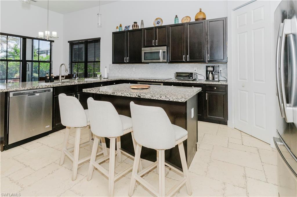 5169 Roma Street South Ave Maria, FL 34142 - Photo 20 of 49 a kitchen with a stove a refrigerator and a dining table with wooden floor