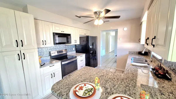 a kitchen with a refrigerator wooden floor dining table and chairs