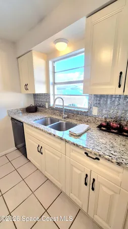 a kitchen with granite countertop a sink a window and cabinets