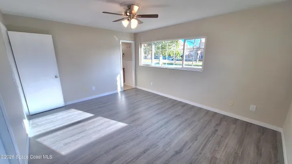 an empty room with wooden floor fan and windows