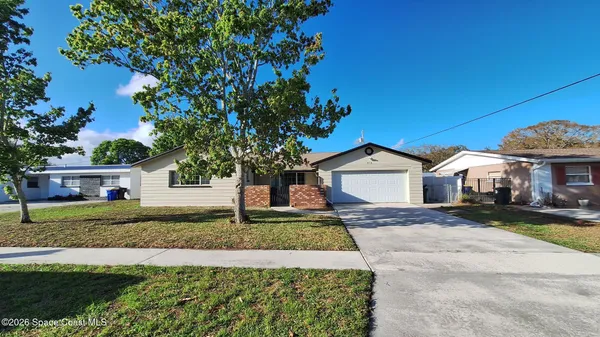a front view of a house with a garden and trees