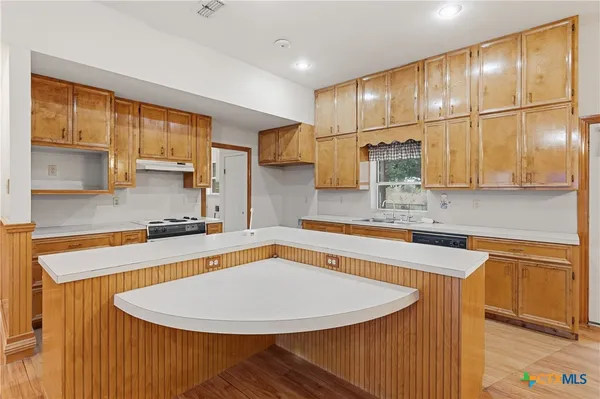 a kitchen with stainless steel appliances granite countertop a sink a stove a refrigerator a washer dryer and white cabinets