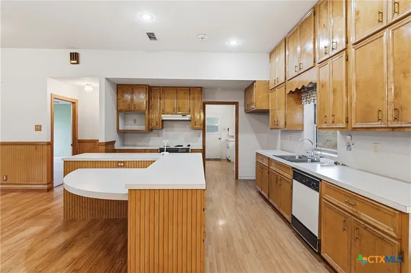 a large kitchen with stainless steel appliances granite countertop a lot of counter space and wooden floors