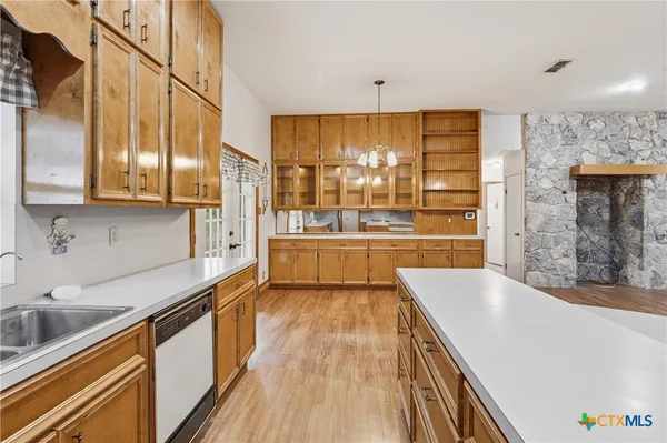 a large kitchen with stainless steel appliances a large counter top a stove a sink and a refrigerator