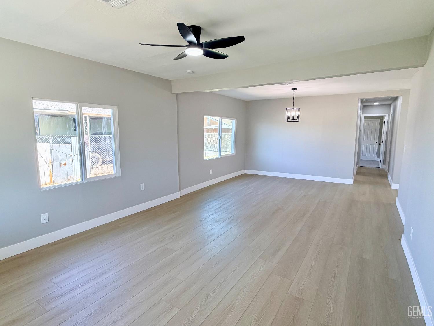 Undisclosed Address Wasco, CA 93280 - Photo 4 of 21 an empty room with wooden floor chandelier fan and windows