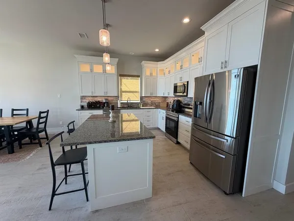 a kitchen with stainless steel appliances granite countertop a stove top oven a sink a dining table and chairs with wooden floor