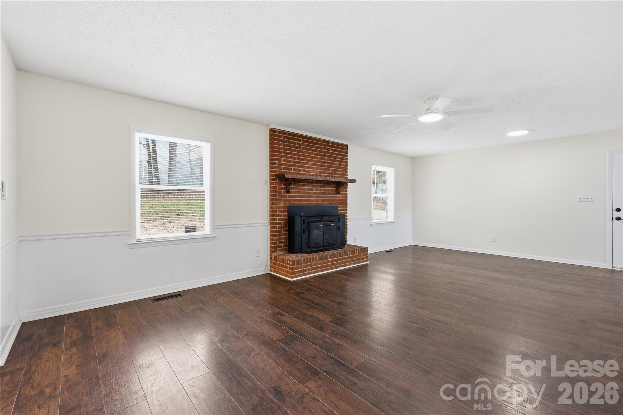 224 Yamasee Road Waxhaw, NC 28173 - Photo 3 of 22 an empty room with wooden floor fireplace and windows
