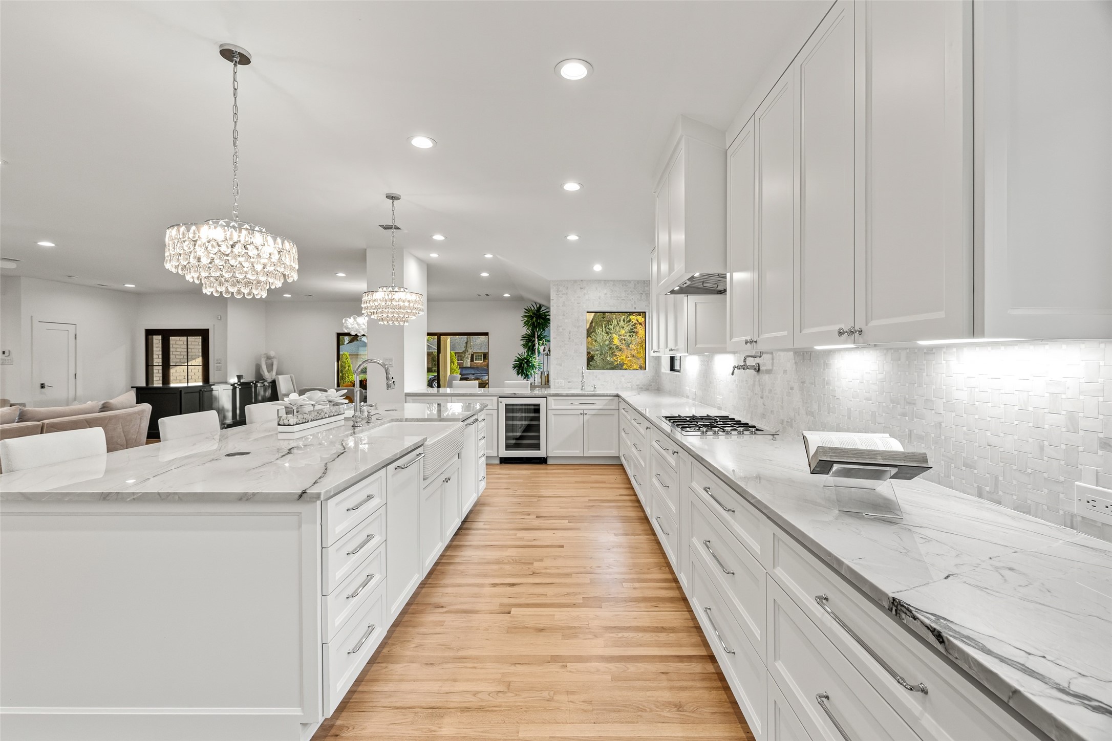 5658 Del Monte Drive Houston, TX 77056 - Photo 6 of 35 This breathtaking, re-imagined kitchen is the true centerpiece of the home—an expansive, light-filled culinary space where luxury design meets modern functionality. Completely transformed from the ground up, the kitchen now stretches with impressive scale, framed by miles of custom cabinetry, showpiece marble countertops, and designer crystal lighting that gives the entire room a refined, glamorous glow.
The oversized waterfall island is a statement of craftsmanship and elegance, offering seating, storag