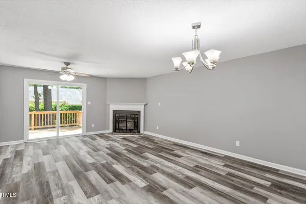 a view of an empty room with wooden floor fireplace and a window
