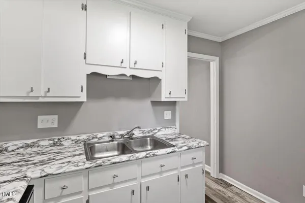 a kitchen with granite countertop white cabinets and a sink