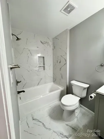 a white toilet sitting next to a bath tub and a shower