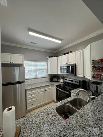 a kitchen with stainless steel appliances granite countertop a sink stove refrigerator and cabinets