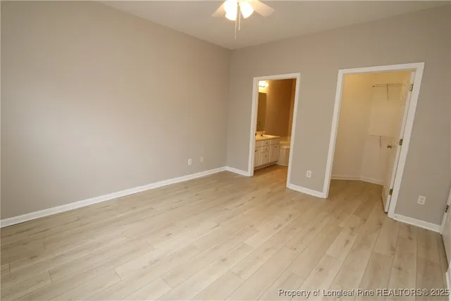 a view of an empty room with wooden floor and a ceiling fan