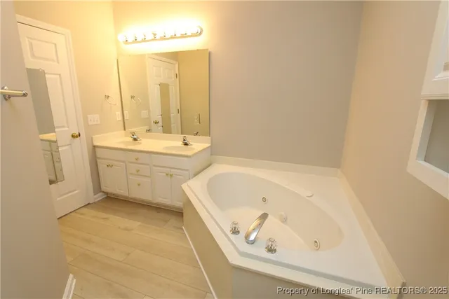 a bathroom with a tub a sink and a large mirror