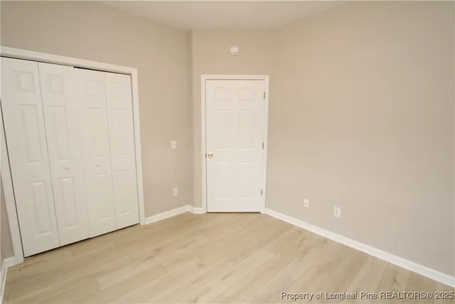 an empty room with wooden floor and closet area