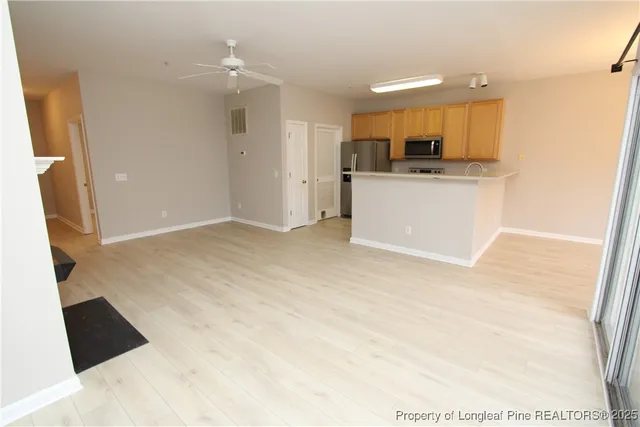 a view of kitchen and empty room with wooden floor