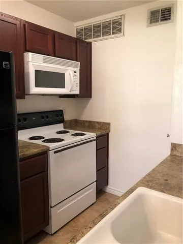 a view of kitchen with stainless steel appliances granite countertop white cabinets and a stove top oven