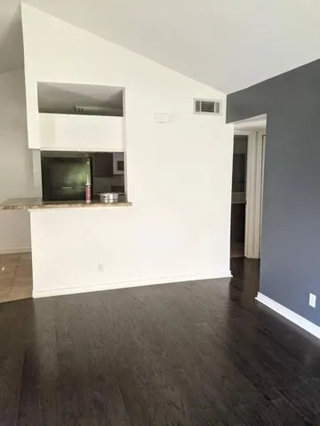 a view of a hallway with wooden floor and a cabinet