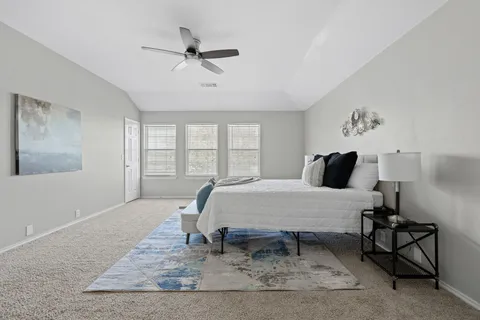 a bed sitting in a room next to a window with a rug and a wooden floor