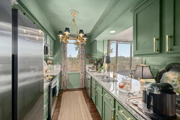 a kitchen with stainless steel appliances granite countertop a sink a stove and a refrigerator