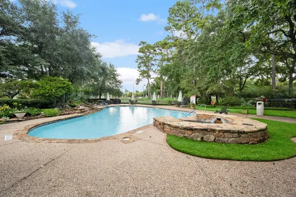 a view of a swimming pool with a fountain and trees in the background