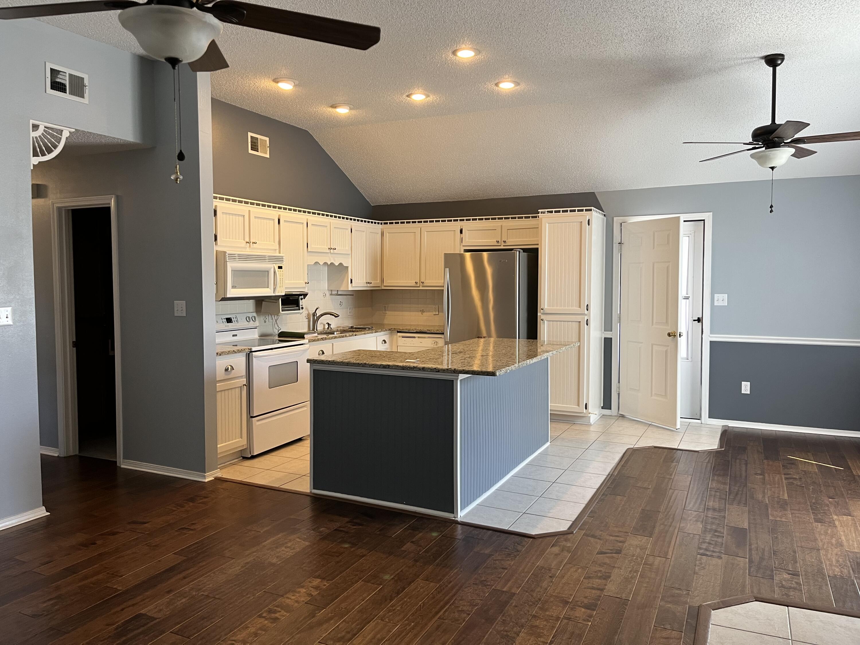 2260 Estate Circle Navarre, FL 32566 - Photo 2 of 14 a kitchen with kitchen island granite countertop wooden floors stainless steel appliances a sink and a refrigerator