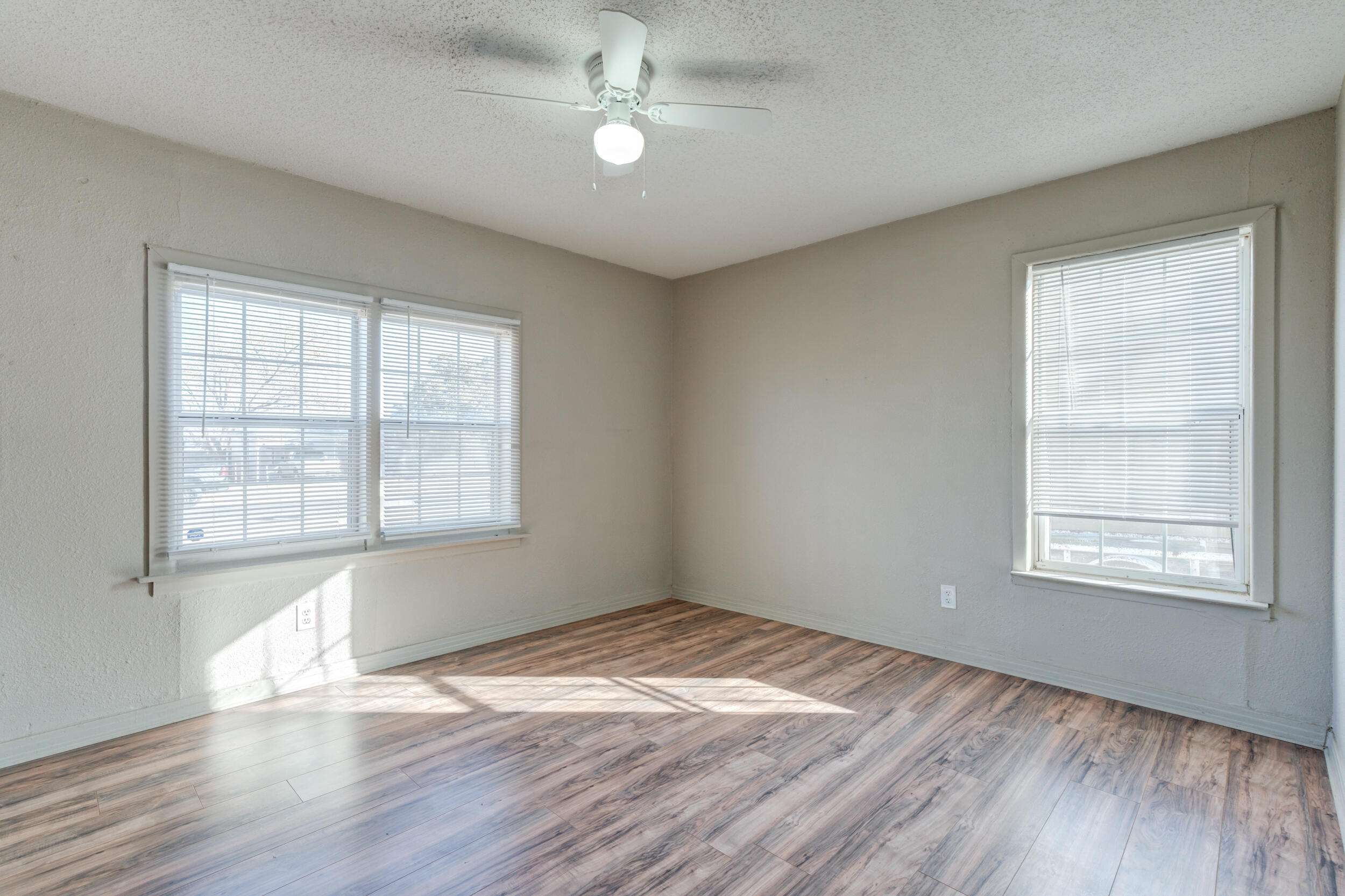 3109 Harvard Street Lubbock, TX 79415 - Photo 24 of 29 an empty room with wooden floor ceiling fan and windows