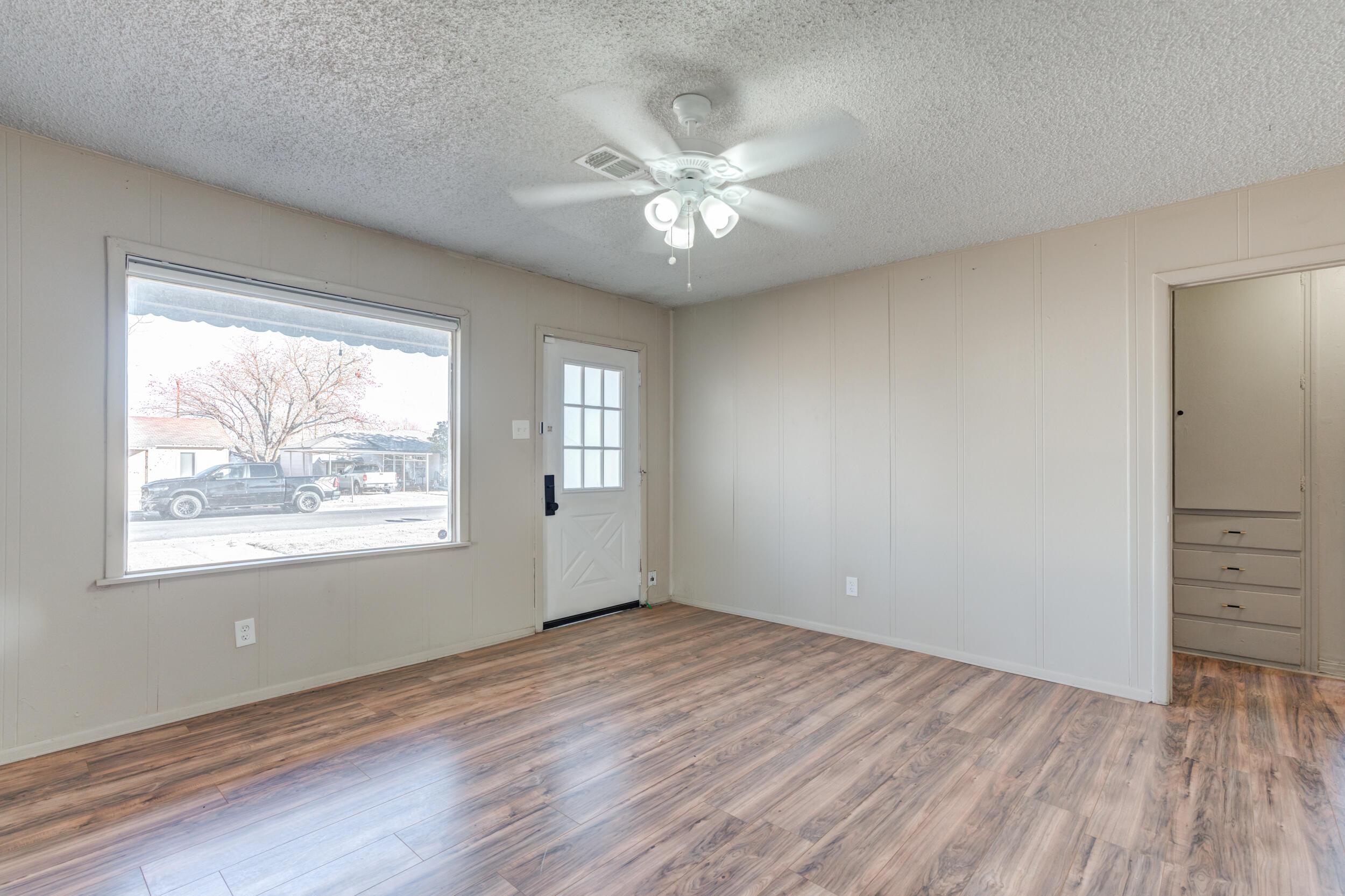 3109 Harvard Street Lubbock, TX 79415 - Photo 4 of 29 an empty room with wooden floor chandelier fan and windows