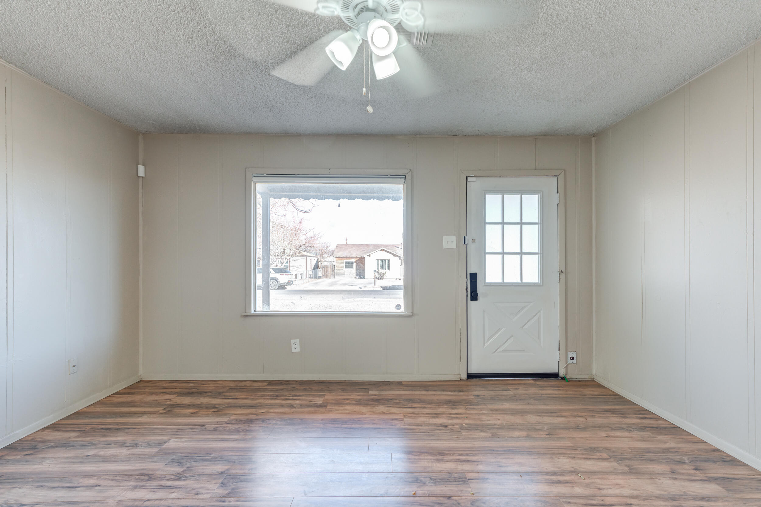 3109 Harvard Street Lubbock, TX 79415 - Photo 5 of 29 an empty room with wooden floor chandelier fan and windows