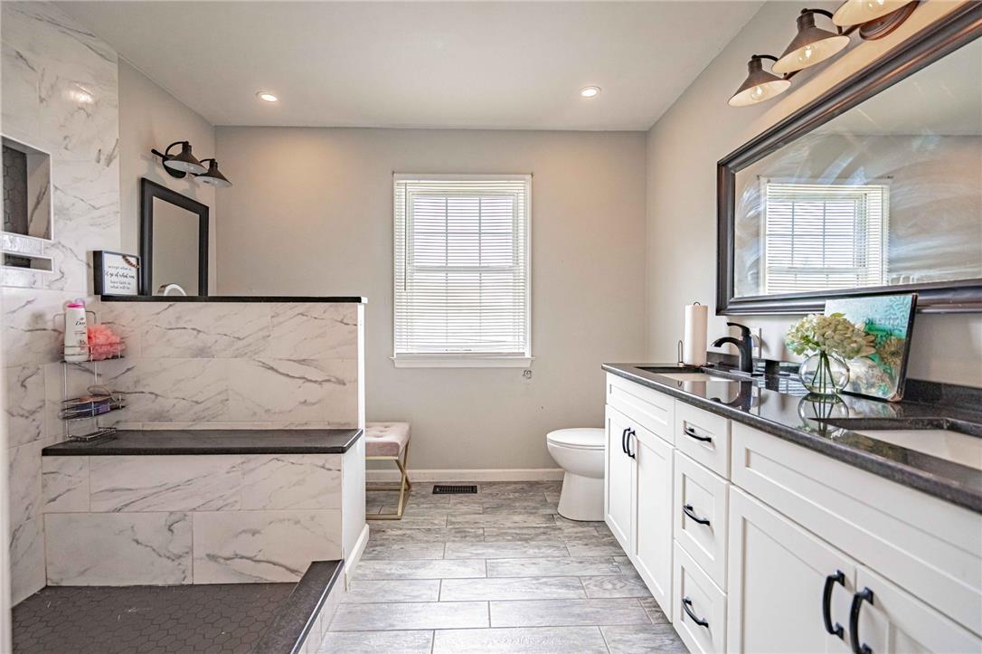 102 Sutton Road Easton, PA 18045 - Photo 41 of 83 Gleaming stone countertops and wood-look tile flooring elevate this modern bathroom design.