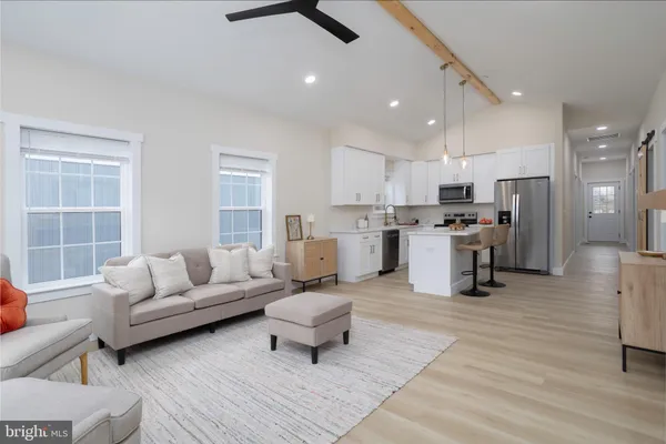 a living room with furniture and kitchen view with wooden floor