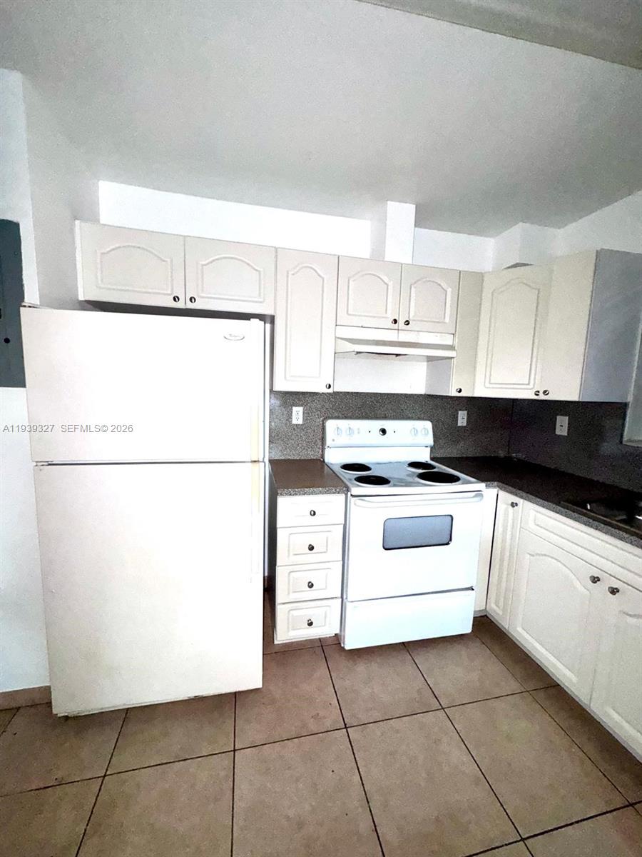 14140 Northeast 2nd Court, Unit 2 Miami, FL 33161 - Photo 2 of 13 a kitchen with a white cabinets and white appliances