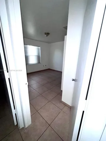 a view of an empty room with wooden floor and a cabinet