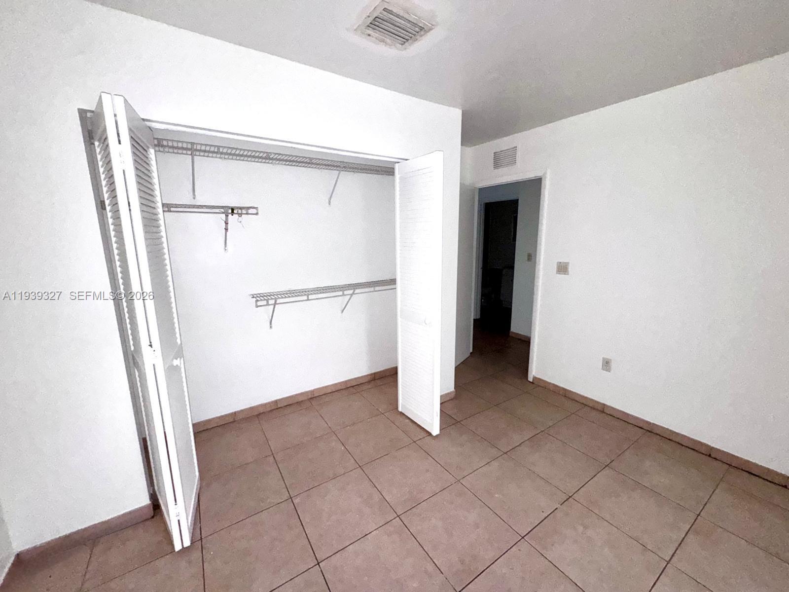 14140 Northeast 2nd Court, Unit 2 Miami, FL 33161 - Photo 9 of 13 a view of an empty room with wooden floor and a cabinet