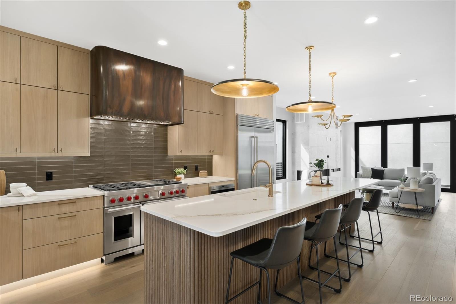 411 Madison Street Denver, CO 80206 - Photo 5 of 38 a kitchen with a stove a kitchen island a sink white cabinets and couches with wooden floor